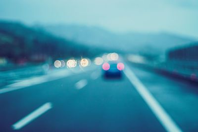 Defocused image of illuminated car on road at night