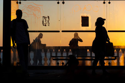 Silhouette at sunset of tree, bus stop and people walking on the edge of porto da barra.