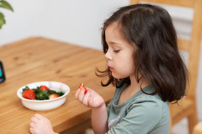 Cute girl eating strawberries while chatting with grandma