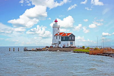 Lighthouse on beach by sea against sky