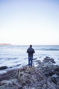 Rear view of man looking at sea against sky