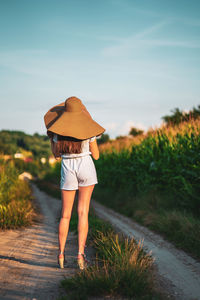 Rear view of woman standing on field against sky