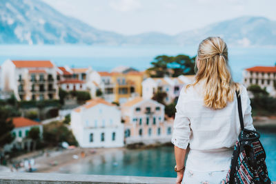 Rear view of woman looking at cityscape against sky