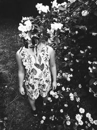 Low section of woman standing by flowering plants on field
