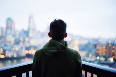 Rear view of man in city against sky at night