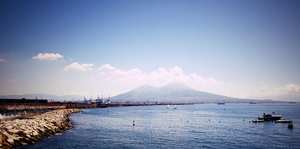 Boats in sea against mountain range