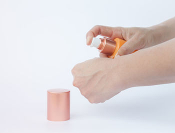 Close-up of hand holding bottle against white background