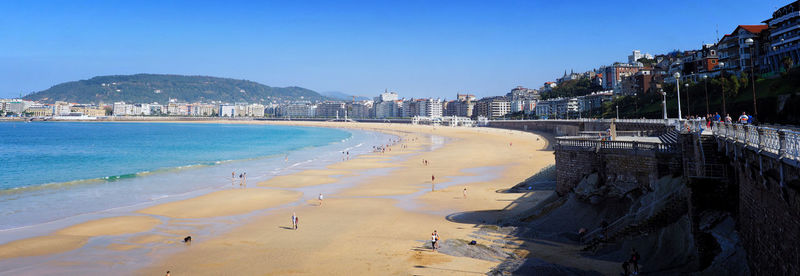 Panoramic view of beach and city buildings against blue sky