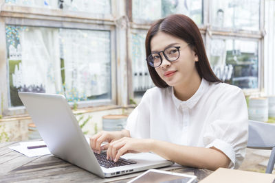 Young woman using phone while sitting on table