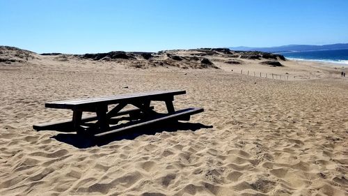 Information sign on sand at beach against clear sky