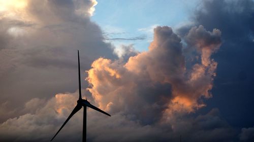Low angle view of silhouette windmills against sky during sunset