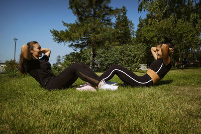 Girl in sportswear on a sunny summer day on the embankment in the park doing fitness and stretching