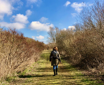 Rear view of woman walking on footpath against sky