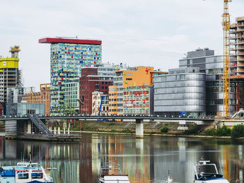 Bridge over river by buildings in city against sky