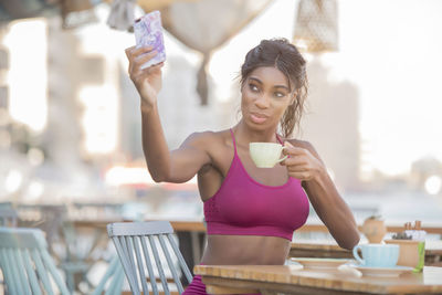 Portrait of young woman drinking glass on table