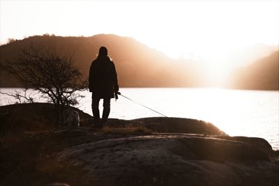 Rear view of silhouette man standing on mountain against sky