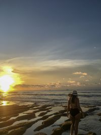 Man standing on beach against sky during sunset