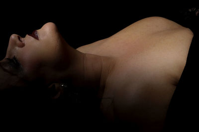 Midsection of woman lying down against black background