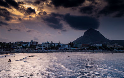 City by sea against sky during sunset