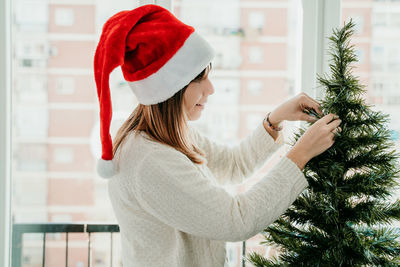 Midsection of woman with christmas tree at home