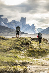 Rear view of men walking on mountain against sky