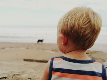 Close-up of boy standing on beach against sky