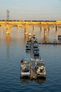 Boats on bridge over river against sky