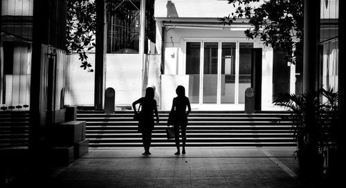 Rear view of silhouette people walking on building