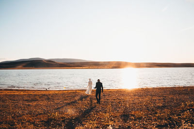 Rear view of couple standing by lake