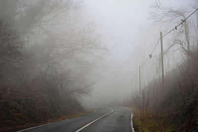 Road amidst bare trees against sky