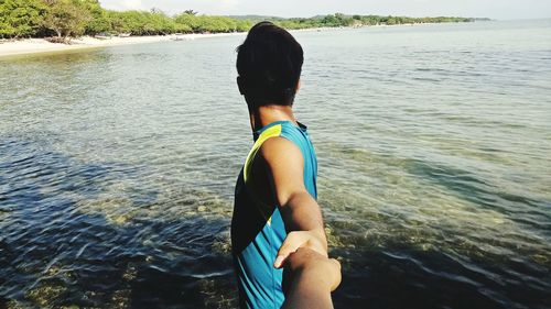 Rear view of woman standing in sea against sky