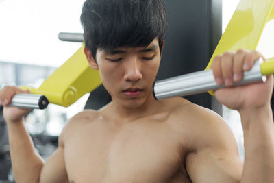 Close-up of shirtless man exercising in gym