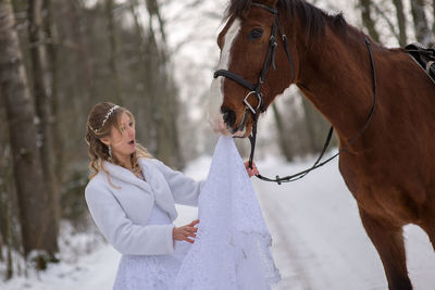 Horse biting bride wedding dress during winter