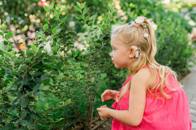 Side view of young woman standing against plants