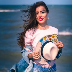 Portrait of smiling young woman standing at beach