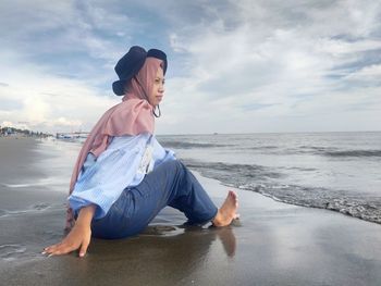 Full length of young woman on beach against sky