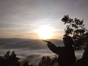 Silhouette woman gesturing against sky during sunset