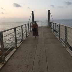 Pier on sea against cloudy sky