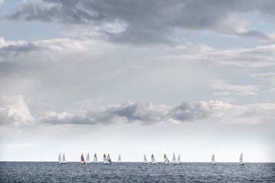 People on beach against cloudy sky