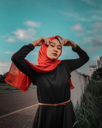 Full length of young woman standing against sky