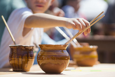 Midsection of boy with holding paintbrush in container on table