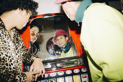 Portrait of man wearing sunglasses with friend seen in mirror at cafe