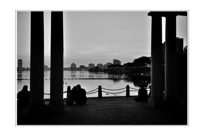 Silhouette people sitting by railing against sky