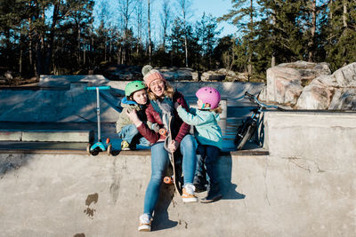 Mom and her kids having fun in a skatepark with bikes and scooters