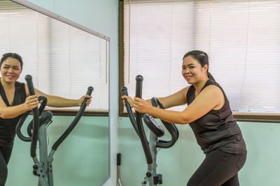 Smiling woman exercising by mirror at gym