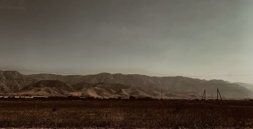 Scenic view of field by mountains against sky