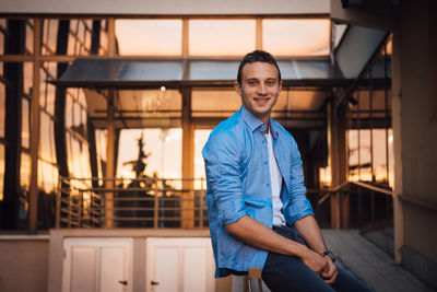 Portrait of young man standing against railing