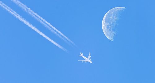 Low angle view of airplane flying against blue sky