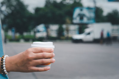 Close-up of hand holding coffee cup on street