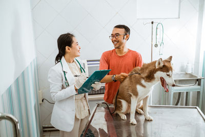 Portrait of young woman with dog on bed at home